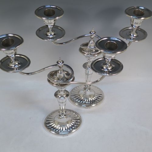 A very pretty pair of Antique Victorian Sterling Silver candelabra in a Neoclassical style with hand-chased fluting and reeded decoration, having removable arms with two lights, with oval bases, reeded scroll-shaped arms, capitals with removable nozzles and drip pans, and reed-edged borders. Made by Walker and Hall of Sheffield in 1901. The dimensions of this fine hand-made pair of antique silver candelabra are height 33 cms (13 inches), and spread across arms 27 cms (10.5 inches).  