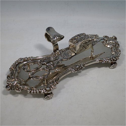 An Antique Georgian Old Sheffield Plated candle scissor snuffer stand and candle scissor snuffer, the stand having an applied floral & scroll border with a cast scroll handle and sitting on four cast scroll feet, the scissor snuffer with matching decoration and all in original working condition. Made in ca. 1820. The dimensions of this fine hand-made antique Old Sheffield Plated snuffer stand and scissors are length 24 cms (9.5 inches), height (inc. handle) 5 cms (2 inches), and width (inc. handle) 11 cms (4.25 inches),   