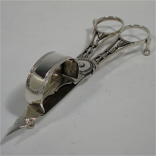 An Antique Georgian Sterling Silver candle scissor snuffer and stand, in a neoclassical style with applied bead-edged borders, and an oval boat-shaped stand. The scissor snuffers made by Walter Brind of London in 1789, and the stand made by John Schofield of London in 1785 (this hallmark has a rare Incuse Duty mark). The dimensions of this fine hand-made antique silver scissor snuffer and stand are length 24 cms (9.5 inches), width 9.5 cms (3.75 inches), and they weigh a total of approx. 213g (6.9 troy ounces).    