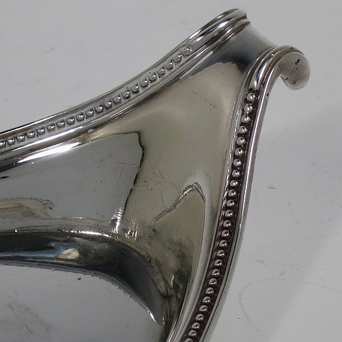 An Antique Georgian Sterling Silver candle scissor snuffer and stand, in a neoclassical style with applied bead-edged borders, and an oval boat-shaped stand. The scissor snuffers made by Walter Brind of London in 1789, and the stand made by John Schofield of London in 1785 (this hallmark has a rare Incuse Duty mark). The dimensions of this fine hand-made antique silver scissor snuffer and stand are length 24 cms (9.5 inches), width 9.5 cms (3.75 inches), and they weigh a total of approx. 213g (6.9 troy ounces).    