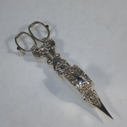 An Antique Georgian Old Sheffield Plated candle scissor snuffer stand and candle scissor snuffer, the stand having an applied floral & scroll border, a hand-chased ground with floral decoration, and sitting on a flat base with four stud feet. The scissor snuffer with matching decoration and all in original working condition. Made in ca. 1830. The dimensions of this fine hand-made antique Old Sheffield Plated snuffer stand and scissors are length 26 cms (10.25 inches), and width 11 cms (4.25 inches),  