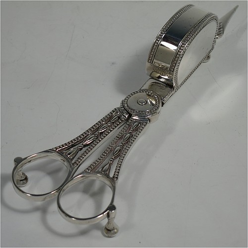 A very pretty Antique Georgian Sterling Silver candle scissor snuffer and stand, in a neoclassical style with applied bead-edged borders, sitting in a hand-pierced and galleried stand with hand-engraved floral decoration. Made in London in 1779, the scissor snuffer by John Buckett, and the stand by James Stamp. The dimensions of this fine hand-made antique silver scissor snuffer and stand are length of stand 20 cms (8 inches), width at widest point 7 cms (2.75 inches), and they weigh a total of approx. 248g (8 troy ounces).    