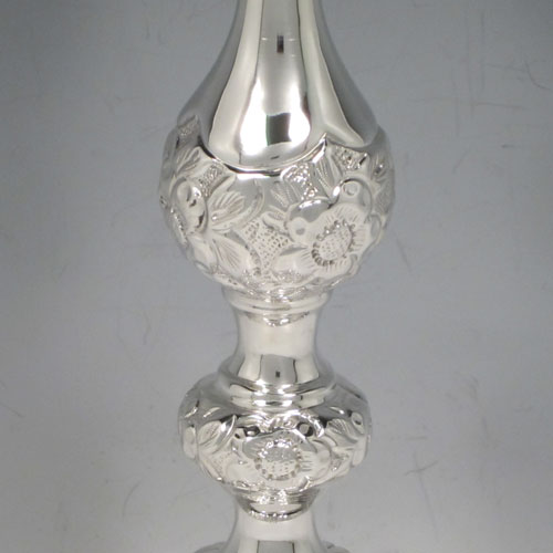 Sterling silver pair of very pretty Sabbath candlesticks, having round baluster bodies with hand-chased floral decoration, with removable nozzles, and sitting on three pierced feet. Made by Jacob Rosenzweig of London in 1917. The dimensions of these fine hand-made silver candlesticks are height 30 cms (11.75 inches), diameter of bases 11 cms (4.25 inches), and they weigh a total of approx. 558g (18 troy ounces). Please note that these candlesticks are not filled.