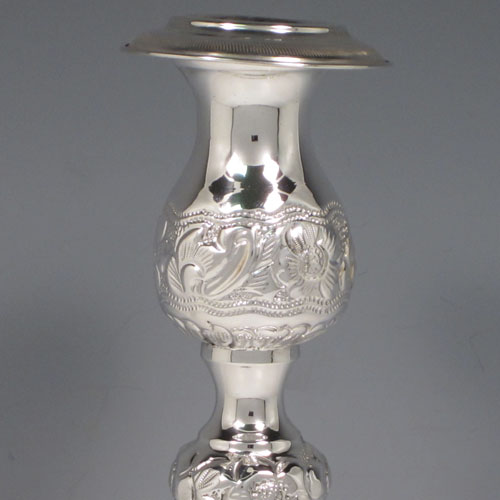 Sterling silver pair of very pretty Sabbath candlesticks, having round baluster bodies with hand-chased floral decoration, with removable nozzles, and sitting on three pierced feet. Made by Jacob Rosenzweig of London in 1917. The dimensions of these fine hand-made silver candlesticks are height 30 cms (11.75 inches), diameter of bases 11 cms (4.25 inches), and they weigh a total of approx. 558g (18 troy ounces). Please note that these candlesticks are not filled.