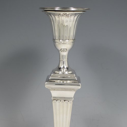 An Antique Victorian Sterling silver pair of large table candlesticks, in a Neoclassical style, having square cross-section bodies with hand-chased fluted decoration, tapering columns, and removable nozzles. Made by William Hutton of London in 1893. The dimensions of these fine hand-made silver candlesticks are height 30.5 cms (12 inches), and 12 cms (4.75 inches) square at bases.    