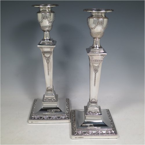 An Antique Victorian Sterling Silver pair of large table candlesticks, in a Neoclassical style, having square cross-section bodies with hand-chased swags and garland decoration, tapering columns, removable nozzles, and bead-edged borders. Made by J. K. Bembridge of Sheffield in 1886. The dimensions of these fine hand-made silver candlesticks are height 28 cms (11 inches), and 11 cms (4.25 inches) square at bases.   