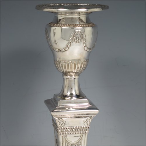 An Antique Victorian Sterling Silver pair of large table candlesticks, in a Neoclassical style, having square cross-section bodies with hand-chased swags and garland decoration, tapering columns, removable nozzles, and bead-edged borders. Made by J. K. Bembridge of Sheffield in 1886. The dimensions of these fine hand-made silver candlesticks are height 28 cms (11 inches), and 11 cms (4.25 inches) square at bases.   