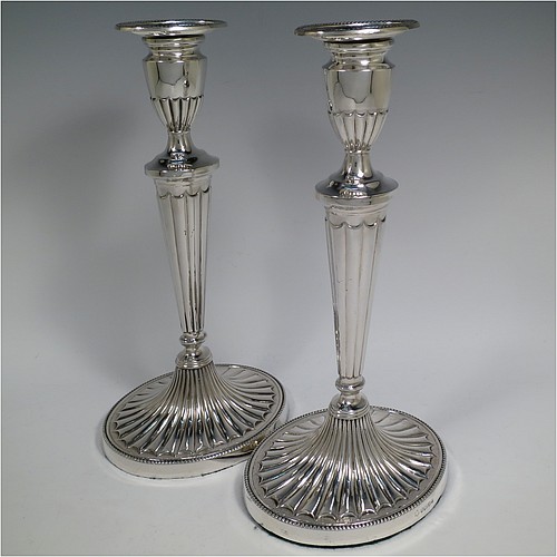 A Sterling Silver very pretty pair of large table candlesticks, in a neoclassical Adams style, having oval bodies with tapering columns and hand-chased inverted flute decoration, with applied bead-edged borders, and removable nozzles. Made by D. J. Silver of London in 1963. The dimensions of these fine hand-made silver candlesticks are height 29 cms (11.5 inches), and length at bases 15 cms (6 inches).