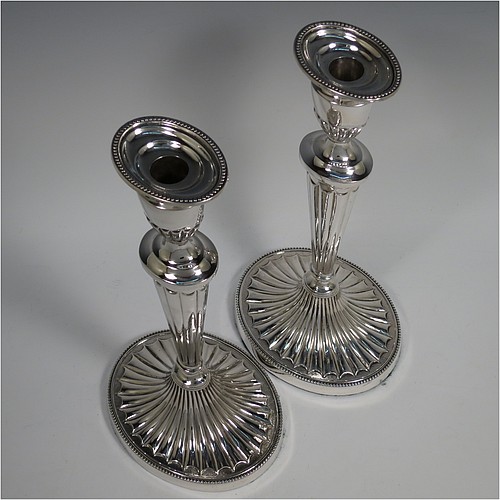 A Sterling Silver very pretty pair of large table candlesticks, in a neoclassical Adams style, having oval bodies with tapering columns and hand-chased inverted flute decoration, with applied bead-edged borders, and removable nozzles. Made by D. J. Silver of London in 1963. The dimensions of these fine hand-made silver candlesticks are height 29 cms (11.5 inches), and length at bases 15 cms (6 inches).