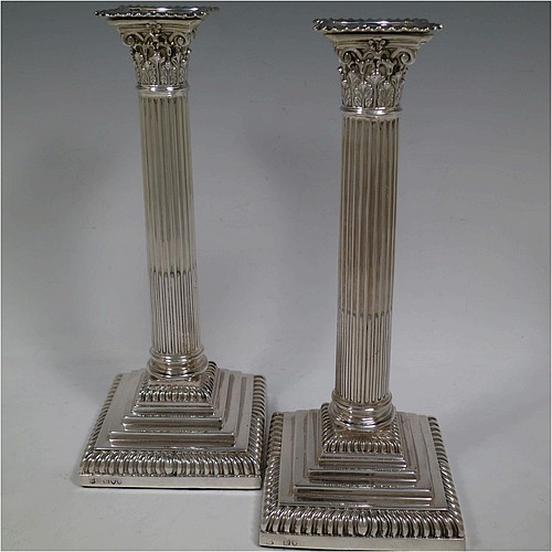 A very handsome and bold pair of Antique Victorian Sterling Silver table candlesticks, in a Neoclassical Corinthian style having square stepped bases, fluted columns, acanthus leaf capitals, removable nozzles, and gadroon borders. Made by Gibson and Langland of London in 1895. The dimensions of this fine hand-made pair of antique silver candlesticks are height 28 cms (11 inches), and their bases are 11.5 cms (4.5 inches) square.    