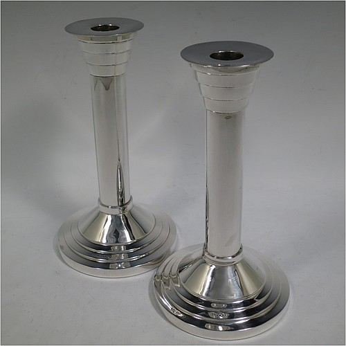 A very unusual and handsome Sterling Silver pair of Art Deco style candlesticks, having round stepped bases, plain round straight-sided columns, with stepped capitals and removable nozzles. Made by Walker and Hall of Sheffield in 1955. The dimensions of these fine hand-made Art Deco style  silver table candlesticks are height 21 cms (8.25 inches), and diameter at base 12 cms (4.75 inches).    