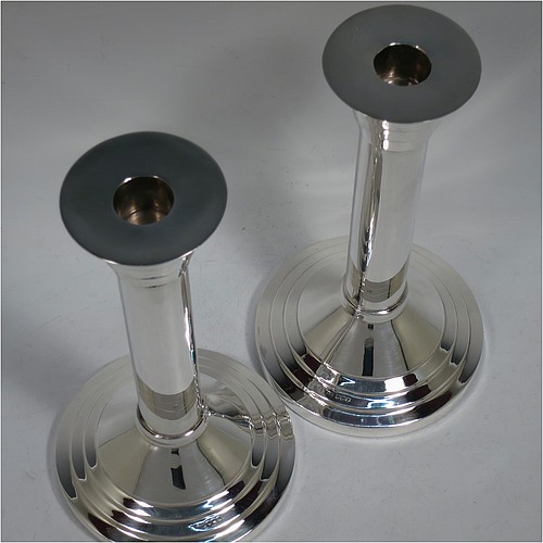 A very unusual and handsome Sterling Silver pair of Art Deco style candlesticks, having round stepped bases, plain round straight-sided columns, with stepped capitals and removable nozzles. Made by Walker and Hall of Sheffield in 1955. The dimensions of these fine hand-made Art Deco style  silver table candlesticks are height 21 cms (8.25 inches), and diameter at base 12 cms (4.75 inches).    