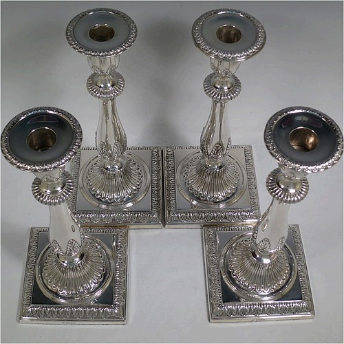 A very pretty set of four Sterling Silver candlesticks in a Neoclassical style, having round baluster bodies with hand-chased anthemion leaf and fluted decoration, with anthemion leaf-edged borders, sitting on square bases with matching decoration, and original removable nozzles. This beautiful set of silver candlesticks were made by Thomas Bradbury of Sheffield in 1921. The dimensions of these fine hand-made silver candlesticks are height 28 cms (11 inches), base 12 cms (4.75 inches) square.    