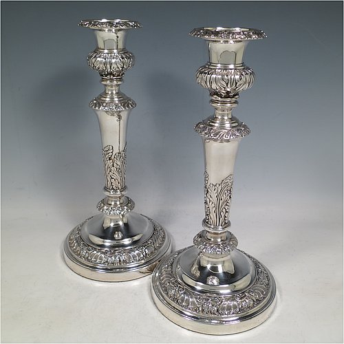 An Antique Georgian Old Sheffield plated very handsome pair of table candlesticks, having round baluster bodies with applied acanthus leaves and hand-chased floral and scroll borders, with removable nozzles, and sitting on round bases. Made in ca. 1830. The dimensions of this fine hand-made pair of Old Sheffield plated candlesticks are height 28 cms (11 inches), and diameter at base 14 cms (5.5 inches).   