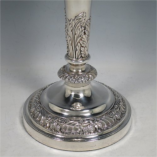 An Antique Georgian Old Sheffield plated very handsome pair of table candlesticks, having round baluster bodies with applied acanthus leaves and hand-chased floral and scroll borders, with removable nozzles, and sitting on round bases. Made in ca. 1830. The dimensions of this fine hand-made pair of Old Sheffield plated candlesticks are height 28 cms (11 inches), and diameter at base 14 cms (5.5 inches).   