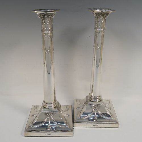 A very pretty pair of Antique Sterling Silver table candlesticks, in a Neoclassical Corinthian style having square bases with hand-chased swags, ribbons and bows, and bead-edged borders, with original removable nozzles. This beautiful pair of antique silver candlesticks were made by Thomas Bradbury and Sons of Sheffield in 1918. The dimensions of this fine hand-made pair antique silver candlesticks are height 31 cms (12.25 inches), and their bases are 12.5 cms (5 inches) square.   