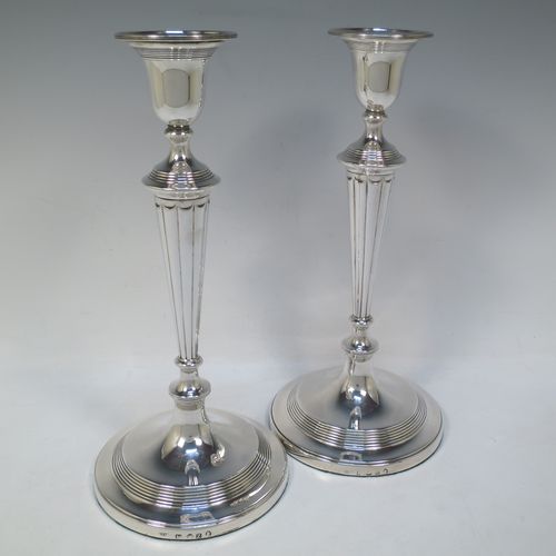 A very handsome pair of Antique Georgian Sterling Silver large table candlesticks in a Neoclassical style, having round bodies with hand-chased reeded borders, tapering columns with hand-chased fluting, and original removable nozzles. Made by John Green and Son Ltd., of Sheffield in 1796. The dimensions of this fine hand-made pair of antique silver candlesticks are height 30 cms (11.75 inches), and diameter at bases 13.5 cms (5.3 inches).   