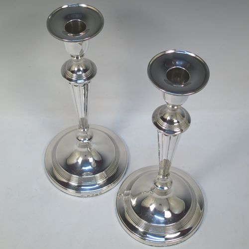 A very handsome pair of Antique Georgian Sterling Silver large table candlesticks in a Neoclassical style, having round bodies with hand-chased reeded borders, tapering columns with hand-chased fluting, and original removable nozzles. Made by John Green and Son Ltd., of Sheffield in 1796. The dimensions of this fine hand-made pair of antique silver candlesticks are height 30 cms (11.75 inches), and diameter at bases 13.5 cms (5.3 inches).   