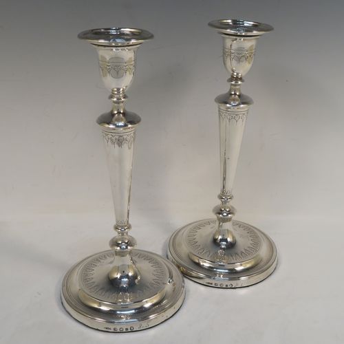 A very elegant pair of Antique Georgian Sterling Silver candlesticks, having round bodies with tapering sides, hand-chased bands of floral decoration, and reeded  borders with original removable nozzles. These handsome antique silver table candlesticks were made by John Parsons and Co., of Sheffield in 1792. The dimensions of these fine hand-made antique Georgian silver candlesticks are height 27 cms (10.5 inches), and diameter of bases are 13 cms (5 inches) diameter.  