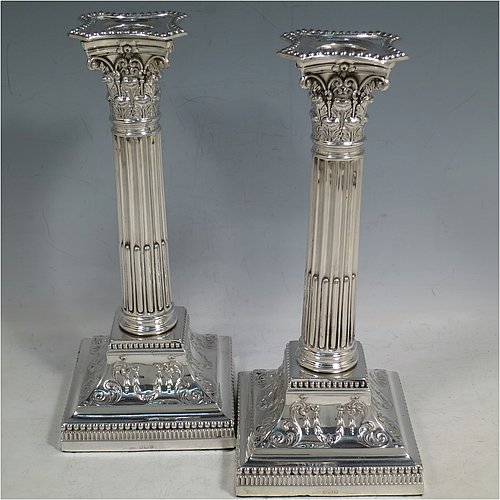 An Antique Sterling Silver pair of candlesticks, in a Neoclassical Corinthian style with square bases and round straight-sided fluted columns, having applied beaded borders, with hand-chased swags and scrolls, and removable nozzles. Made by James Dixon of Sheffield in 1912. The dimensions of this fine pair of hand-made antique silver candlesticks are height 22 cms (8.75 inches), and the bases are 9.5 cms (3.75 inches) square.    