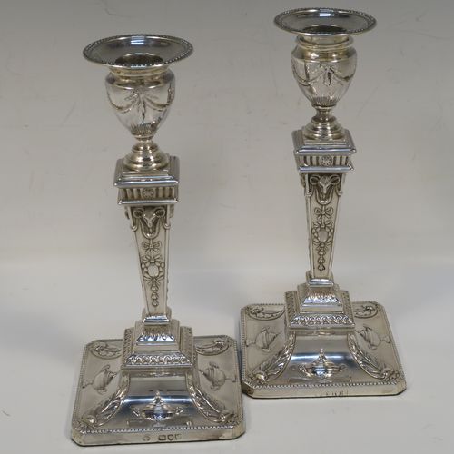 A very pretty pair of Antique Victorian Sterling Silver Neoclassical style candlesticks, having bead-edged borders, with hand-chased rams heads, swags, ribbons, and tureens, with removable nozzles, and square bases. These beautiful antique silver candlesticks were made by William Hutton and Sons of London in 1895. The dimensions of this fine hand-made pair of antique silver candlesticks are height 20 cms (8 inches), and the bases are 9 cms (3.5 inches) square.   