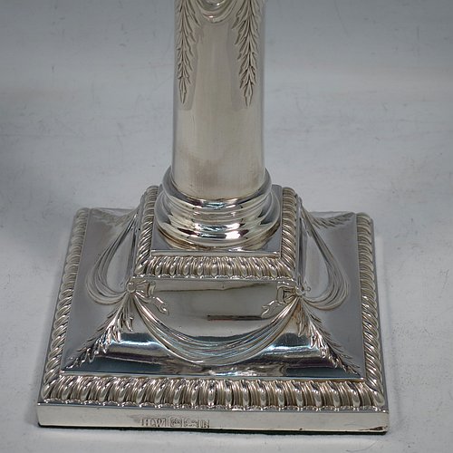 An Antique Edwardian Sterling Silver pair of candlesticks, in a Neoclassical Corinthian style with square bases and round straight-sided columns, having applied gadroon borders, hand-chased bows with swag decoration, and removable nozzles. Made by Henry Wilkinson of Sheffield in 1902. The dimensions of this fine pair of hand-made antique silver candlesticks are height 19 cms (7.5 inches), and the bases are 10 cms (4 inches) square.    