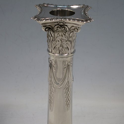 An Antique Edwardian Sterling Silver pair of candlesticks, in a Neoclassical Corinthian style with square bases and round straight-sided columns, having applied gadroon borders, hand-chased bows with swag decoration, and removable nozzles. Made by Henry Wilkinson of Sheffield in 1902. The dimensions of this fine pair of hand-made antique silver candlesticks are height 19 cms (7.5 inches), and the bases are 10 cms (4 inches) square.    