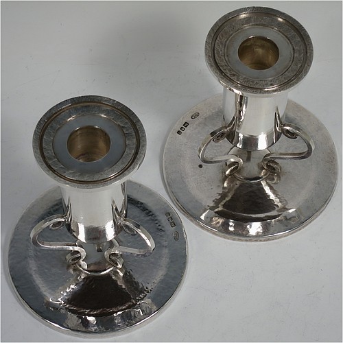 A Sterling Silver pair of modernistic style candlesticks, having round bodies with straight sides, attached to round flat hand-hammered bases with three scroll feet. Made by John Crawford Adams of London in 1981. The dimensions of these fine hand-made silver candlesticks are height 12 cms (4.75 inches), diameter at base 11 cms (4.3 inches), with a total weight of approx. 578g (18.6 troy ounces). Please note that these candlesticks are not loaded. 