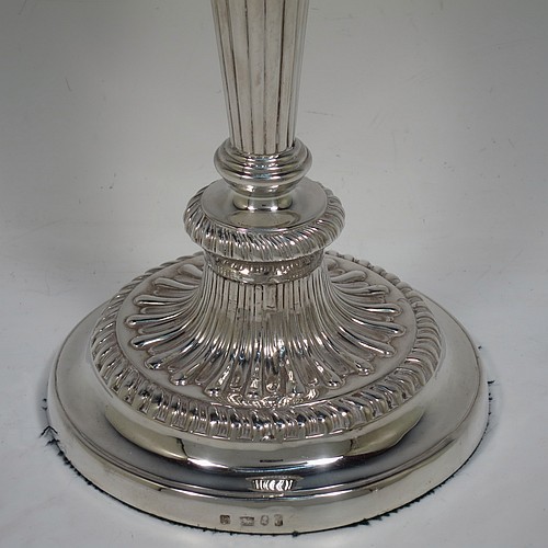 A very handsome pair of Antique Georgian Sterling Silver candlesticks, having hand-chased fluted decoration and applied gadroon borders, with their original removable nozzles, and round pedestal bases. Made by John and Thomas Settle of Sheffield in 1826. The dimensions of this fine hand-made pair of antique silver candlesticks are height 28 cms (11 inches), and diameter of bases 14 cms (5.5 inches).   