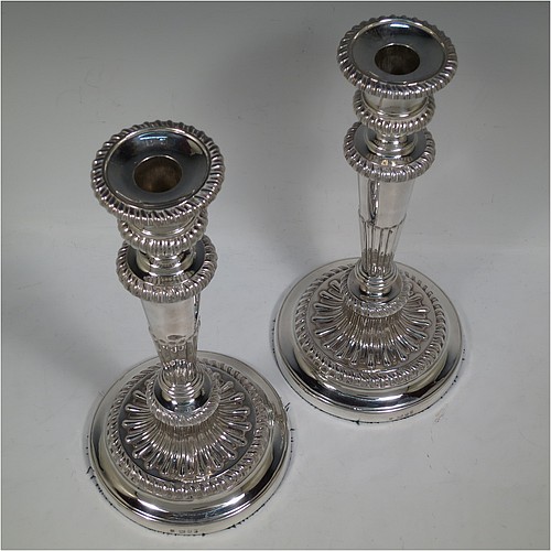 A very handsome pair of Antique Georgian Sterling Silver candlesticks, having hand-chased fluted decoration and applied gadroon borders, with their original removable nozzles, and round pedestal bases. Made by John and Thomas Settle of Sheffield in 1826. The dimensions of this fine hand-made pair of antique silver candlesticks are height 28 cms (11 inches), and diameter of bases 14 cms (5.5 inches).   