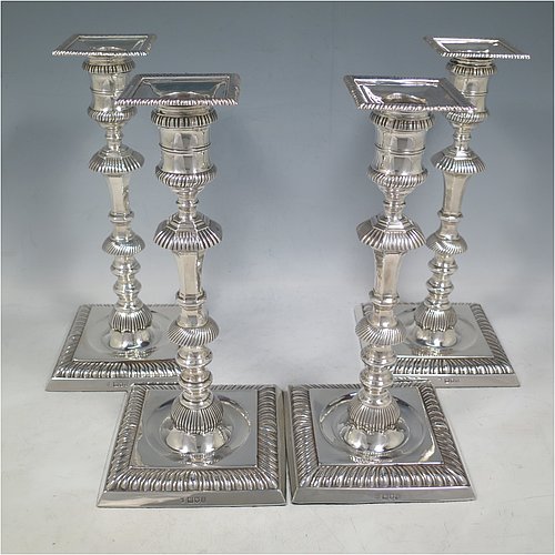 An Antique Edwardian Sterling Silver handsome set of four candlesticks in a George I style, having round baluster bodies, with removable square nozzles, and sitting on square bases, all with hand-chased fluted decoration and applied gadroon borders. Made by Thomas Bradbury of London in 1904. The dimensions of these fine hand-made antique silver table candlesticks are height 23.5 cms (9.25 inches), and the bases are 11 cms (4.3 inches) square.    