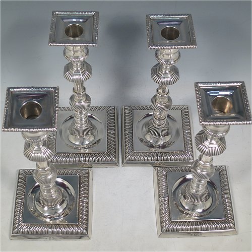 An Antique Edwardian Sterling Silver handsome set of four candlesticks in a George I style, having round baluster bodies, with removable square nozzles, and sitting on square bases, all with hand-chased fluted decoration and applied gadroon borders. Made by Thomas Bradbury of London in 1904. The dimensions of these fine hand-made antique silver table candlesticks are height 23.5 cms (9.25 inches), and the bases are 11 cms (4.3 inches) square.    