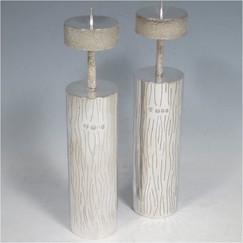 A Sterling Silver pair of candlesticks in a Modernistic style, having cylindrical bodies with hand-chased tree-bark decoration, together with capitals and candle spikes with an unusual stippled finish. Made by Michael Bensted of London in 1975. The dimensions of these fine hand-made pair of silver table candlesticks are height 19 cms (7.5 inches), diameter 4 cms (1.5 inches), and they weigh a total of approx. 437g (14.1 troy ounces). Please note that these candlesticks are not filled.