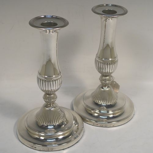 An elegant pair of Antique Georgian Sterling Silver candlesticks, having round baluster bodies, with removable nozzles, and sitting on round bases, with central hand-chased fluted decoration. This handsome pair of antique silver candlesticks were made by John Greene Co., of Sheffield in 1804. The dimensions of these fine hand-made antique silver table candlesticks are height 18.5 cms (7.25 inches), and the bases are 11 cms (4.25 inches) in diameter.