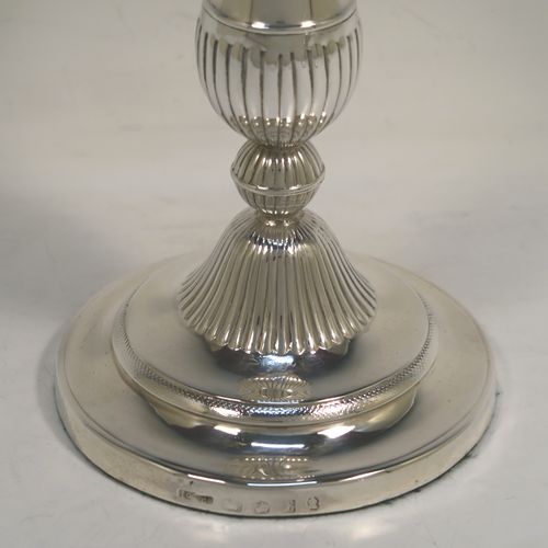 An elegant pair of Antique Georgian Sterling Silver candlesticks, having round baluster bodies, with removable nozzles, and sitting on round bases, with central hand-chased fluted decoration. This handsome pair of antique silver candlesticks were made by John Greene Co., of Sheffield in 1804. The dimensions of these fine hand-made antique silver table candlesticks are height 18.5 cms (7.25 inches), and the bases are 11 cms (4.25 inches) in diameter.