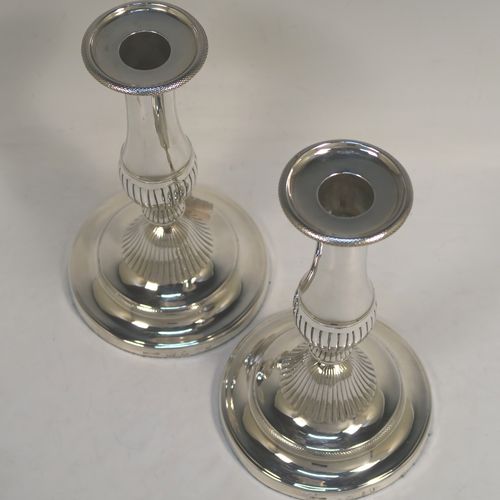 An elegant pair of Antique Georgian Sterling Silver candlesticks, having round baluster bodies, with removable nozzles, and sitting on round bases, with central hand-chased fluted decoration. This handsome pair of antique silver candlesticks were made by John Greene Co., of Sheffield in 1804. The dimensions of these fine hand-made antique silver table candlesticks are height 18.5 cms (7.25 inches), and the bases are 11 cms (4.25 inches) in diameter.