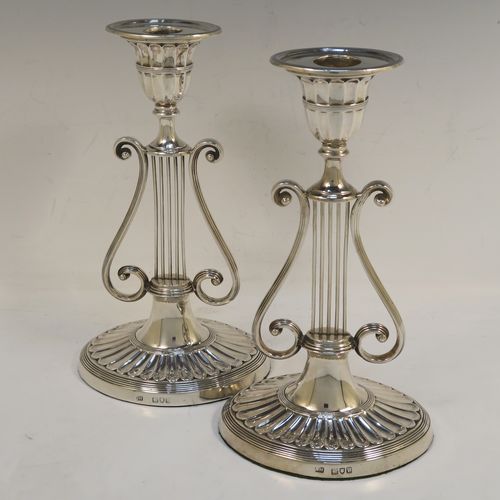 An unusual and pretty Antique Victorian Sterling Silver pair of candlesticks, having Lyre harp musical instrument style bodies, with fluted and reeded decoration, removable nozzles, and sitting on oval bases. This beautiful pair of Lyre Harp candlesticks were made by George Hancock of London in 1901. The dimensions of these fine hand-made pair of antique silver candlesticks are height 20.5 cms (8 inches), and width at base 11.5 cms (4.5 inches).   