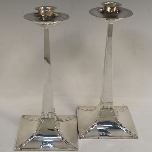 A handsome pair of Arts and Crafts style Antique Sterling Silver candlesticks, having plain square cross-section tapering columns, plain round nozzles with drip pans, and sitting on square bases with rivetted style decorated corners. These elegant antique silver Arts and Crafts candlesticks were made by James Dixon and Sons of Sheffield in 1918. The dimensions of these fine hand-made pair of antique silver table candlesticks are height 21.5 cms (8.5 inches), and the bases are 10 cms (4 inches) square.   