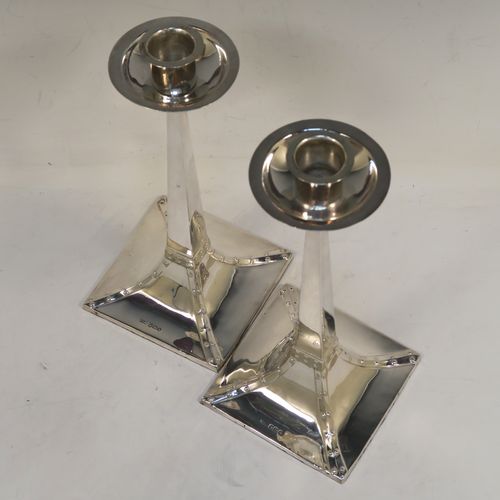 A handsome pair of Arts and Crafts style Antique Sterling Silver candlesticks, having plain square cross-section tapering columns, plain round nozzles with drip pans, and sitting on square bases with rivetted style decorated corners. These elegant antique silver Arts and Crafts candlesticks were made by James Dixon and Sons of Sheffield in 1918. The dimensions of these fine hand-made pair of antique silver table candlesticks are height 21.5 cms (8.5 inches), and the bases are 10 cms (4 inches) square.   