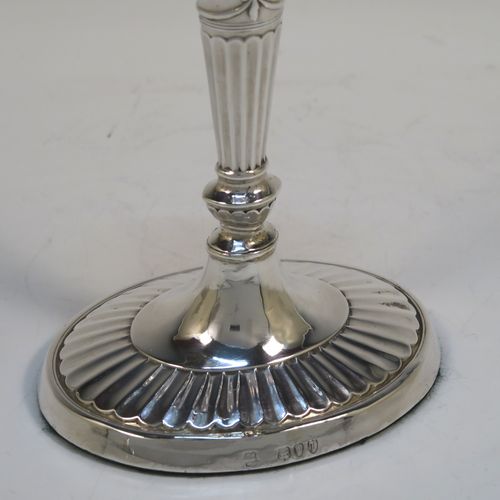 A very pretty pair of Antique Victorian Sterling Silver candlesticks, having Neoclassical style oval shaped bodies, with hand-chased fluted decoration, reeded borders, bows and swags, and removable nozzles. These beautiful antique silver candlesticks were made by Holland, Aldwinckle, and Slater of London in 1894. The dimensions of these fine hand-made pair of antique silver table candlesticks are height 18.5 cms (7.25 inches), length at base 10 cms (4 inches), and width at base 7.5 cms (3 inches).  