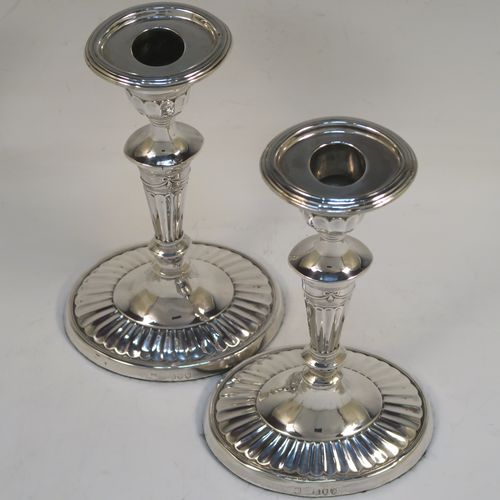 A very pretty pair of Antique Victorian Sterling Silver candlesticks, having Neoclassical style oval shaped bodies, with hand-chased fluted decoration, reeded borders, bows and swags, and removable nozzles. These beautiful antique silver candlesticks were made by Holland, Aldwinckle, and Slater of London in 1894. The dimensions of these fine hand-made pair of antique silver table candlesticks are height 18.5 cms (7.25 inches), length at base 10 cms (4 inches), and width at base 7.5 cms (3 inches).  