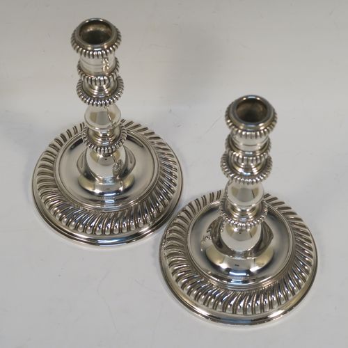 A very handsome pair of cast Britannia standard Silver candlesticks in an early Queen Ann style, having round baluster bodies with applied and hand-chased fluted borders. These elegant cast silver candlesticks were made by Wakely and Wheeler of London in 1967. The dimensions of this fine pair of hand-made cast sterling silver table candlesticks are height 17 cms (6.75 inches), the bases are 11 cms (4.25 inches) in diameter, and the total weight is 871g (28 troy ounces).   