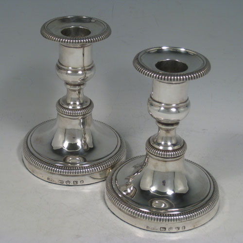 Antique Georgian sterling silver pair of candlesticks, having round bases with baluster bodies, gadroon borders, and removable nozzles. Made by James Roberts and Co., of Sheffield in 1809. The dimensions of these fine hand-made silver candlesticks are height 12.5 cms (5 inches), and the diameter of the bases are 9.5 cms (3.75 inches).    