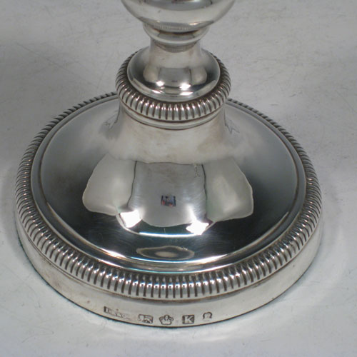 Antique Georgian sterling silver pair of candlesticks, having round bases with baluster bodies, gadroon borders, and removable nozzles. Made by James Roberts and Co., of Sheffield in 1809. The dimensions of these fine hand-made silver candlesticks are height 12.5 cms (5 inches), and the diameter of the bases are 9.5 cms (3.75 inches).    