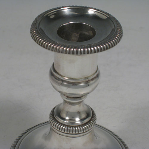 Antique Georgian sterling silver pair of candlesticks, having round bases with baluster bodies, gadroon borders, and removable nozzles. Made by James Roberts and Co., of Sheffield in 1809. The dimensions of these fine hand-made silver candlesticks are height 12.5 cms (5 inches), and the diameter of the bases are 9.5 cms (3.75 inches).    