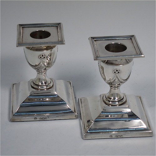 An Antique Victorian Sterling Silver very pretty pair of small candlesticks, having neoclassical style decoration with rectangular bases, with hand-chased bows and swags, and removable nozzles with applied reeded borders. Made by William Angus Fraser of Sheffield in 1894. The dimensions of these fine hand-made antique silver candlesticks are height 8 cms (3.25 inches), and the bases are 7 cms (2.75 inches) square.    