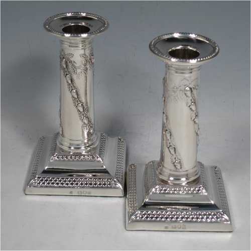 An Antique Edwardian Sterling silver pair of candlesticks, in a Neoclassical style with bead- edged borders, having straight round columns with hand-chased oak leaves and acorns, sitting on stepped bases, and with removable nozzles. Made by Thomas Bradbury of London in 1896. The dimensions of this fine pair of hand-made silver candlesticks are height 13 cms (5.25 inches), and the bases are 8 cms (3 inches) square.   