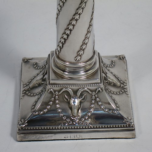 A very striking Antique Victorian Sterling Silver pair of candlesticks, in a Corinthian style with bead-edged borders, removable nozzles, columns with twisted bluebell garlands, and square bases with hand-chased swags of flowers and rams heads. Made by William Hutton of London in 1900. The dimensions of this fine pair of hand-made antique silver candlesticks are height 15 cms (6 inches), and the bases are 8 cms (3.25 inches) square.    