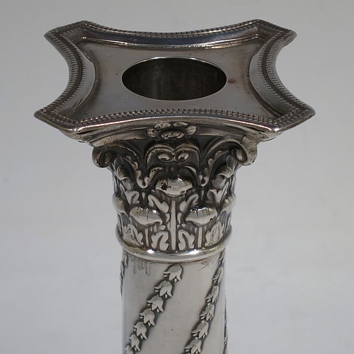 A very striking Antique Victorian Sterling Silver pair of candlesticks, in a Corinthian style with bead-edged borders, removable nozzles, columns with twisted bluebell garlands, and square bases with hand-chased swags of flowers and rams heads. Made by William Hutton of London in 1900. The dimensions of this fine pair of hand-made antique silver candlesticks are height 15 cms (6 inches), and the bases are 8 cms (3.25 inches) square.    