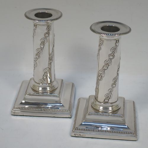 A very pretty Antique Edwardian Sterling Silver pair of candlesticks, in a Corinthian style with hand-chased floral and leaf decoration on the columns and bead-edged borders, removable nozzles, and square stepped bases. Made by Hawksworth, Eyre and Co., of Sheffield in 1909. The dimensions of this fine pair of hand-made antique silver candlesticks are height 13 cms (5 inches), and the bases are 8 cms (3.25 inches) square.  